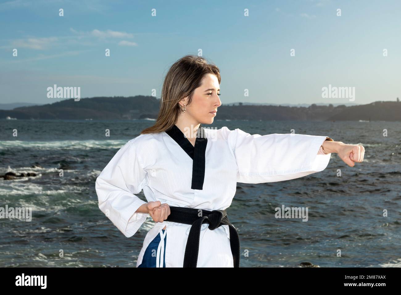 young woman in kimono doing martial arts on the beach Stock Photo