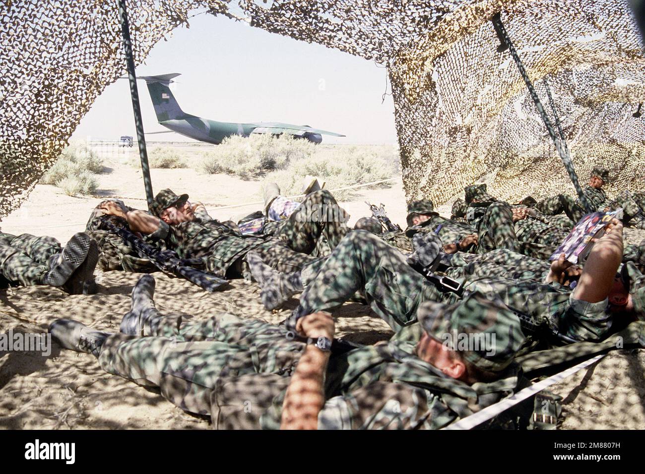 Marines nap under camouflage netting while a Air Force C141B