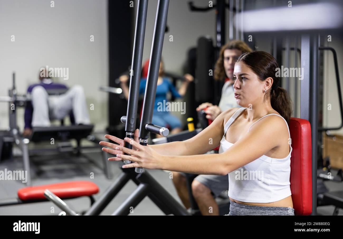 Sporty woman works on special simulator for development of pectoral muscles  Stock Photo - Alamy