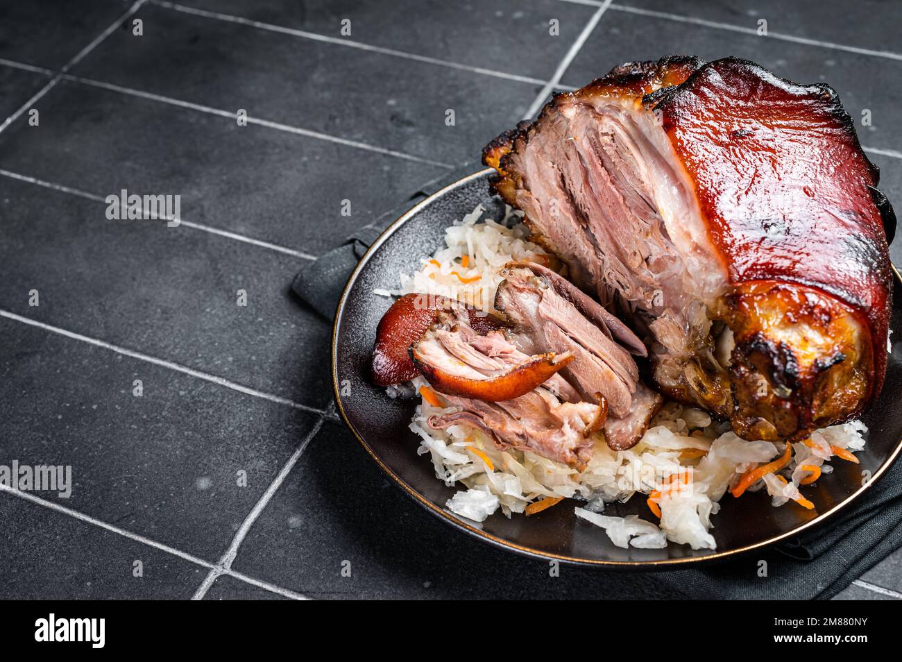 Roast Pork Ham Hock, knuckle with Sauerkraut on a plate. Black