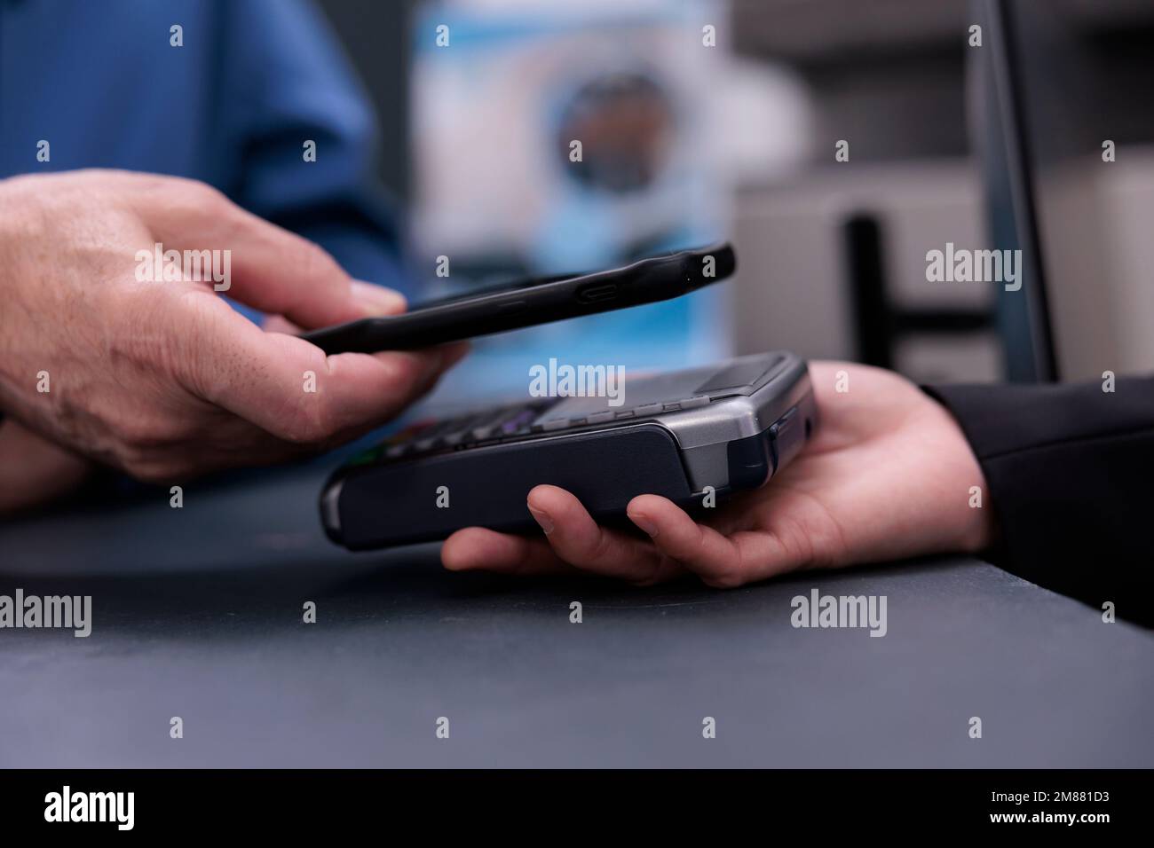 Senior patient paying for health care treatment and consultation with phone using contactless payment at hospital counter desk after finishing appointment. Medicine support service and concept Stock Photo