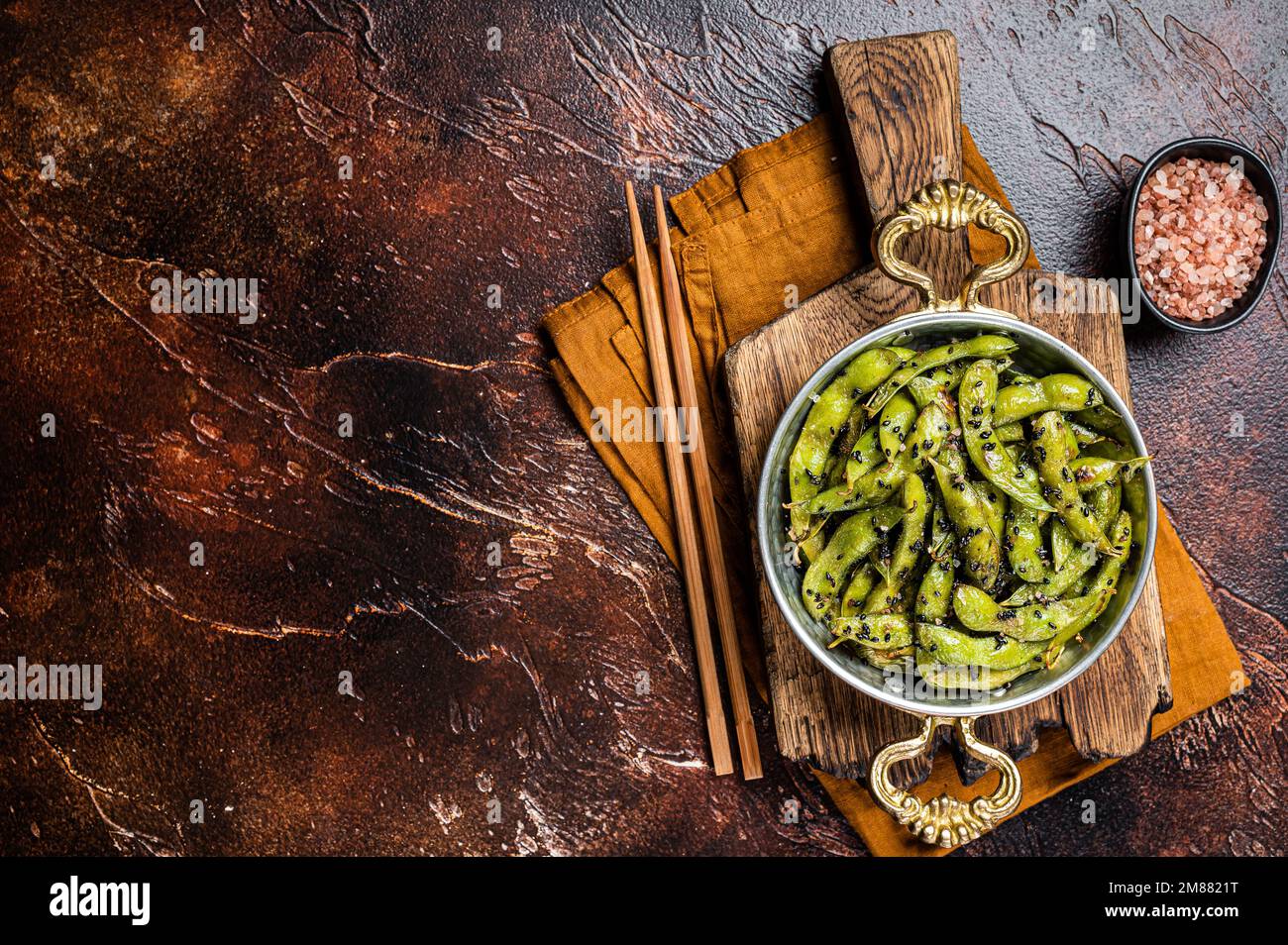 Roasted green Edamame Soy Beans with sea salt and sesame seeds in a skillet. Dark background. Top view. Copy space. Stock Photo