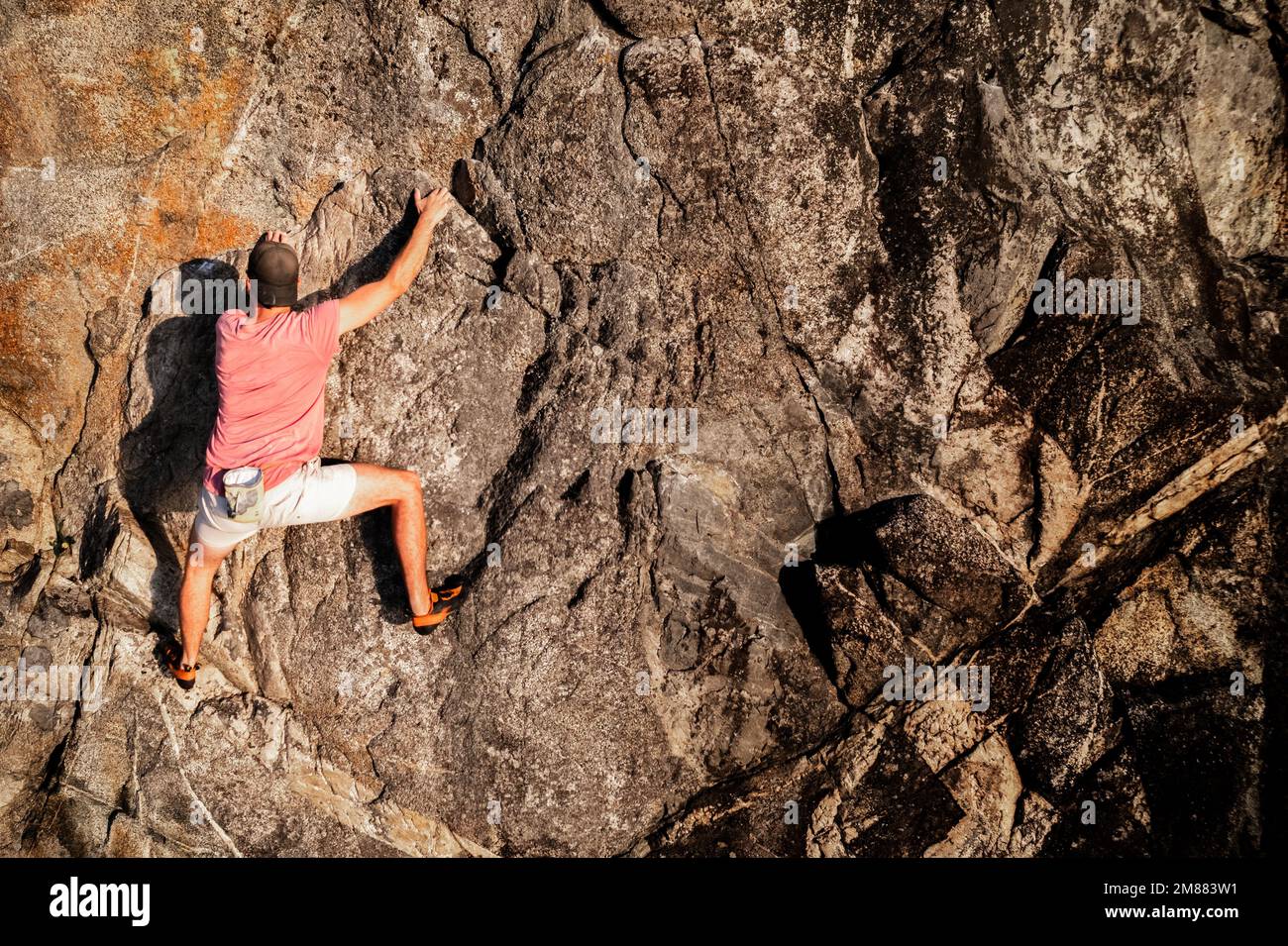 Male rock climber over the ocean, free solo, no rope, adventure sport, rock face, cliff. Stock Photo