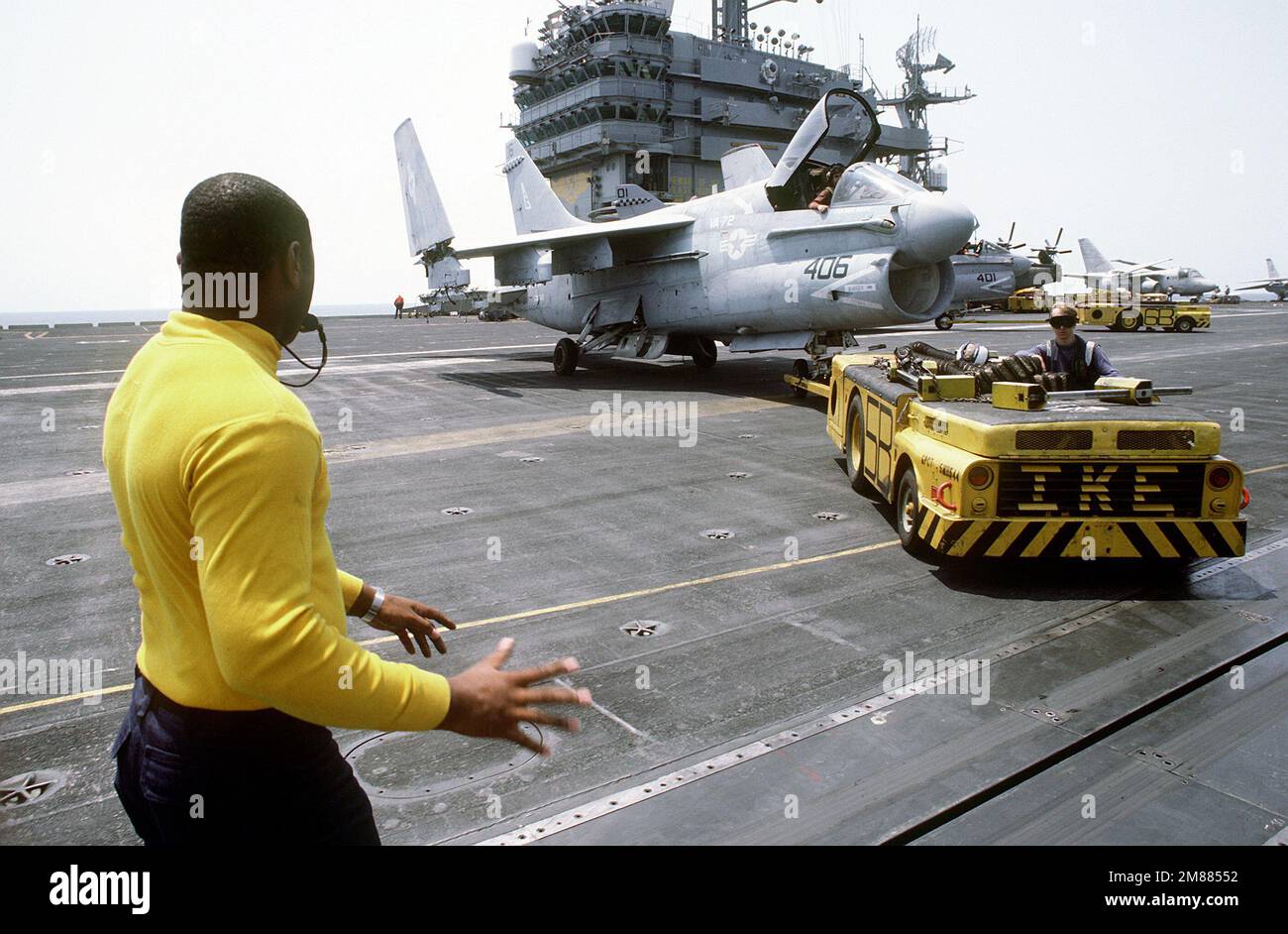 A plane director supervises the towing of an Attack Squadron 72 (VA72