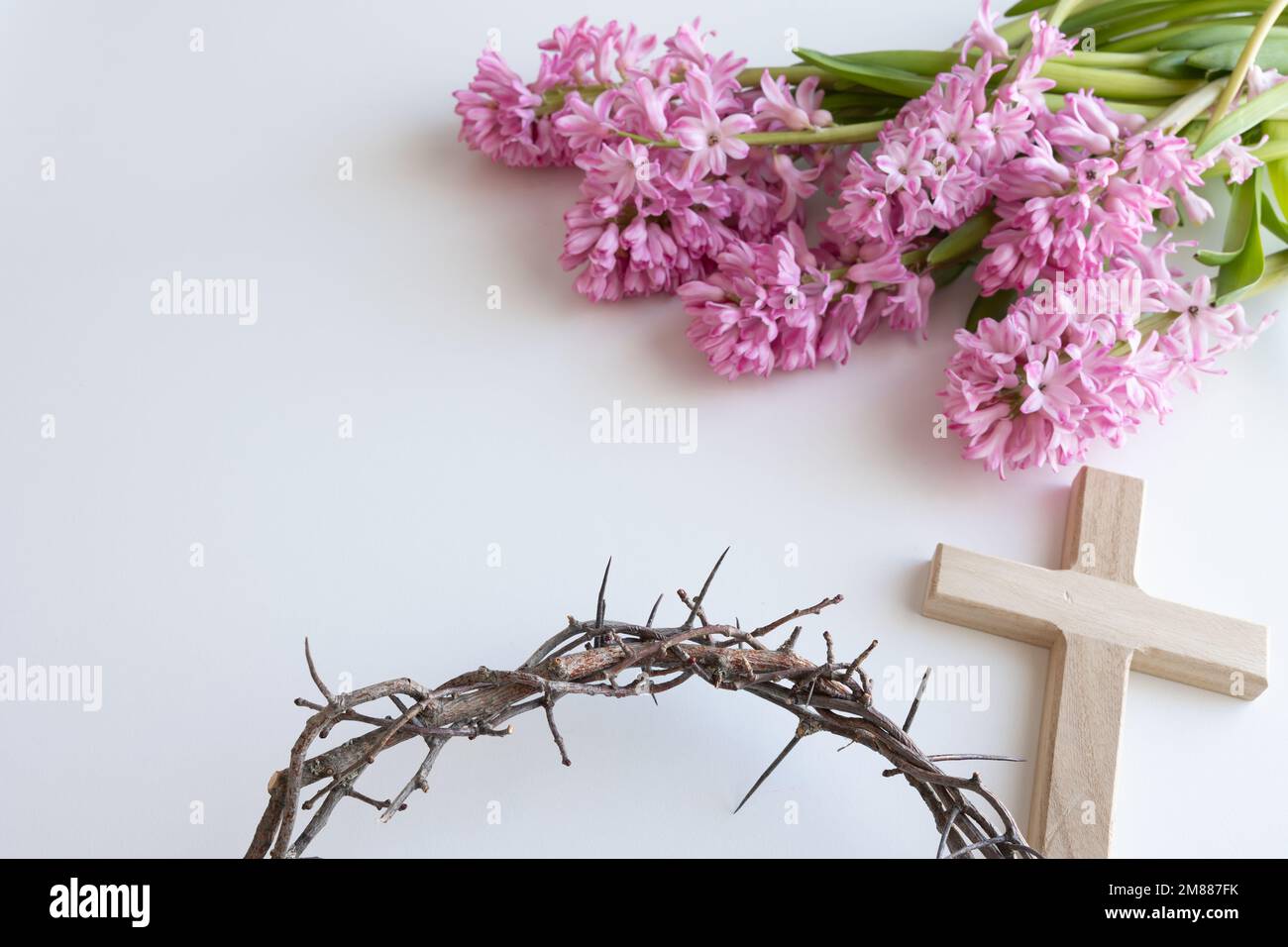 Simple wood cross and crown of thorns with pink hyacinth flowers on a white background with copy space Stock Photo