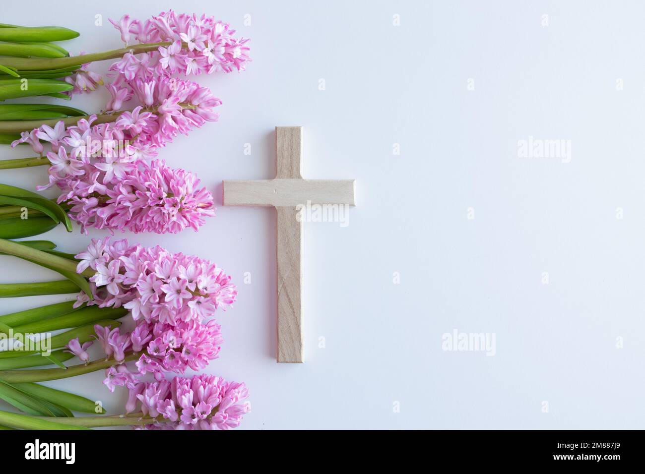 Simple wood Christian cross on a white background with a bouquet of