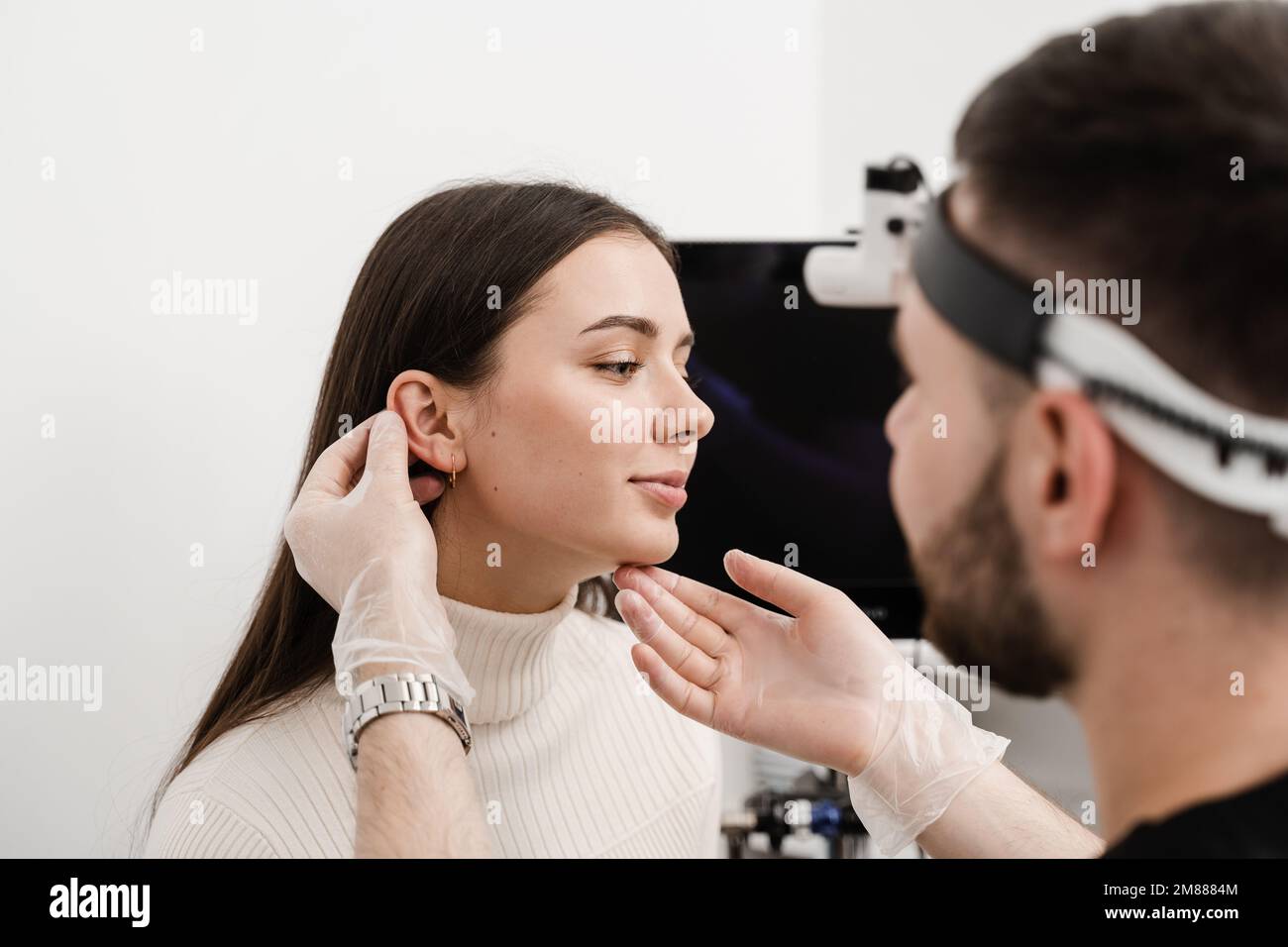 Otoplasty ear surgery. Surgeon doctor examines girl ears before