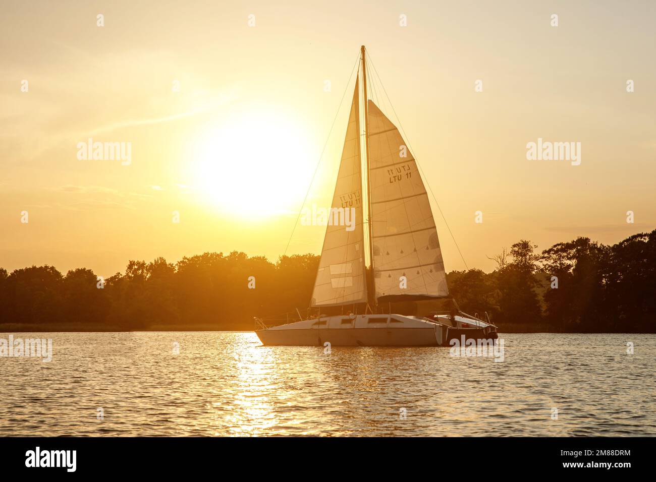 The yacht sails on the lake at sunset Stock Photo - Alamy