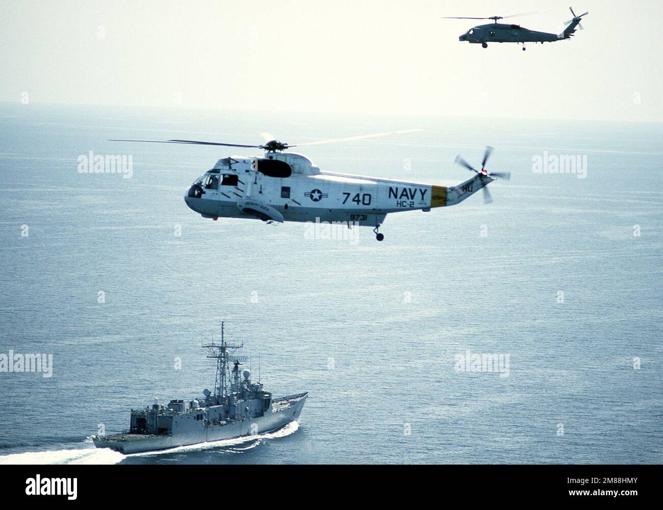 An air-to-air left view of a Helicopter Combat Support Squadron 2 (HC-2) SH-3 Sea King helicopter and an SH-60B Sea Hawk helicopter over the guided missile frigate USS RENTZ (FFG-46). Country: Unknown Stock Photo