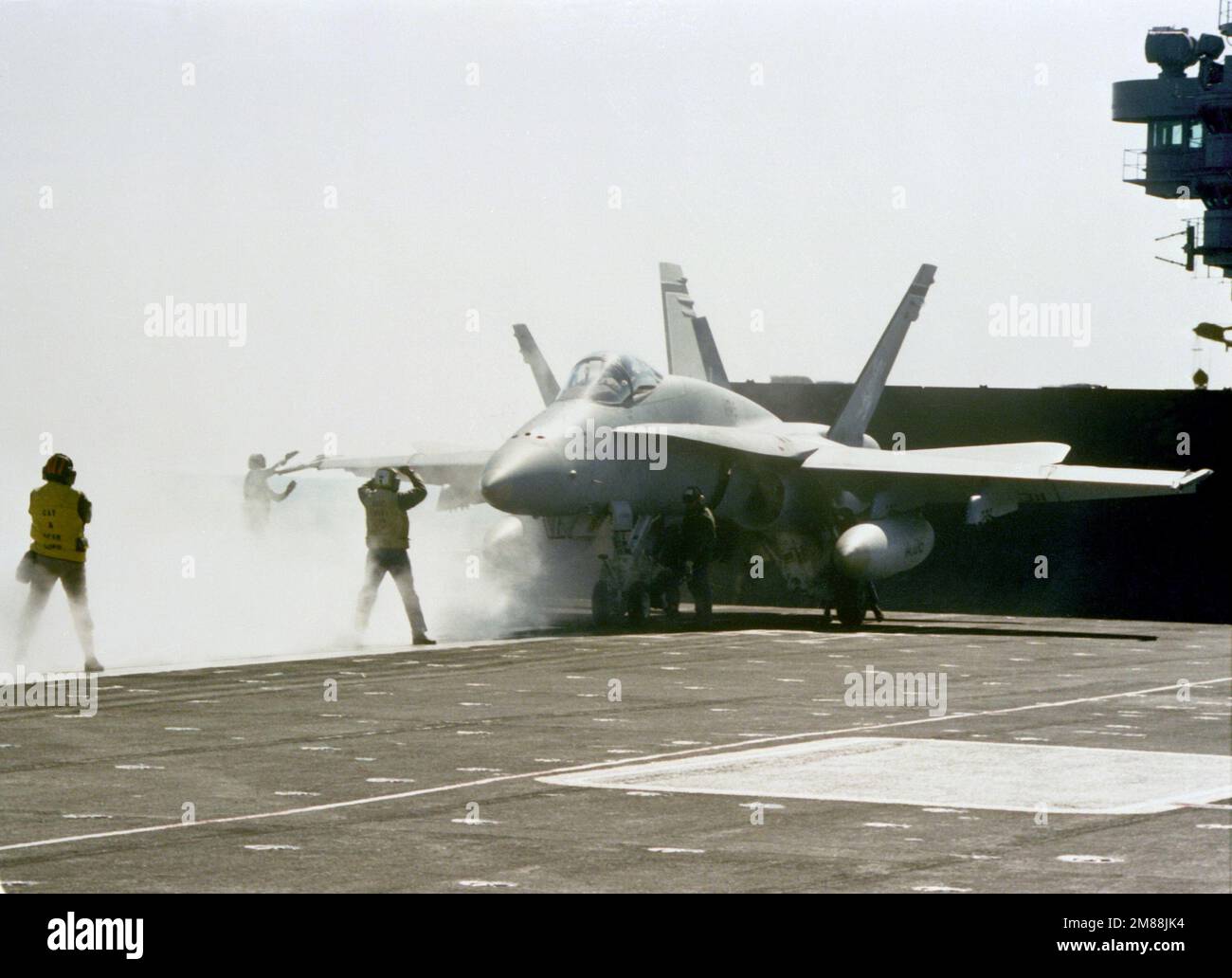Flight deck crewmen position an F-18A Hornet aircraft on a catapult ...