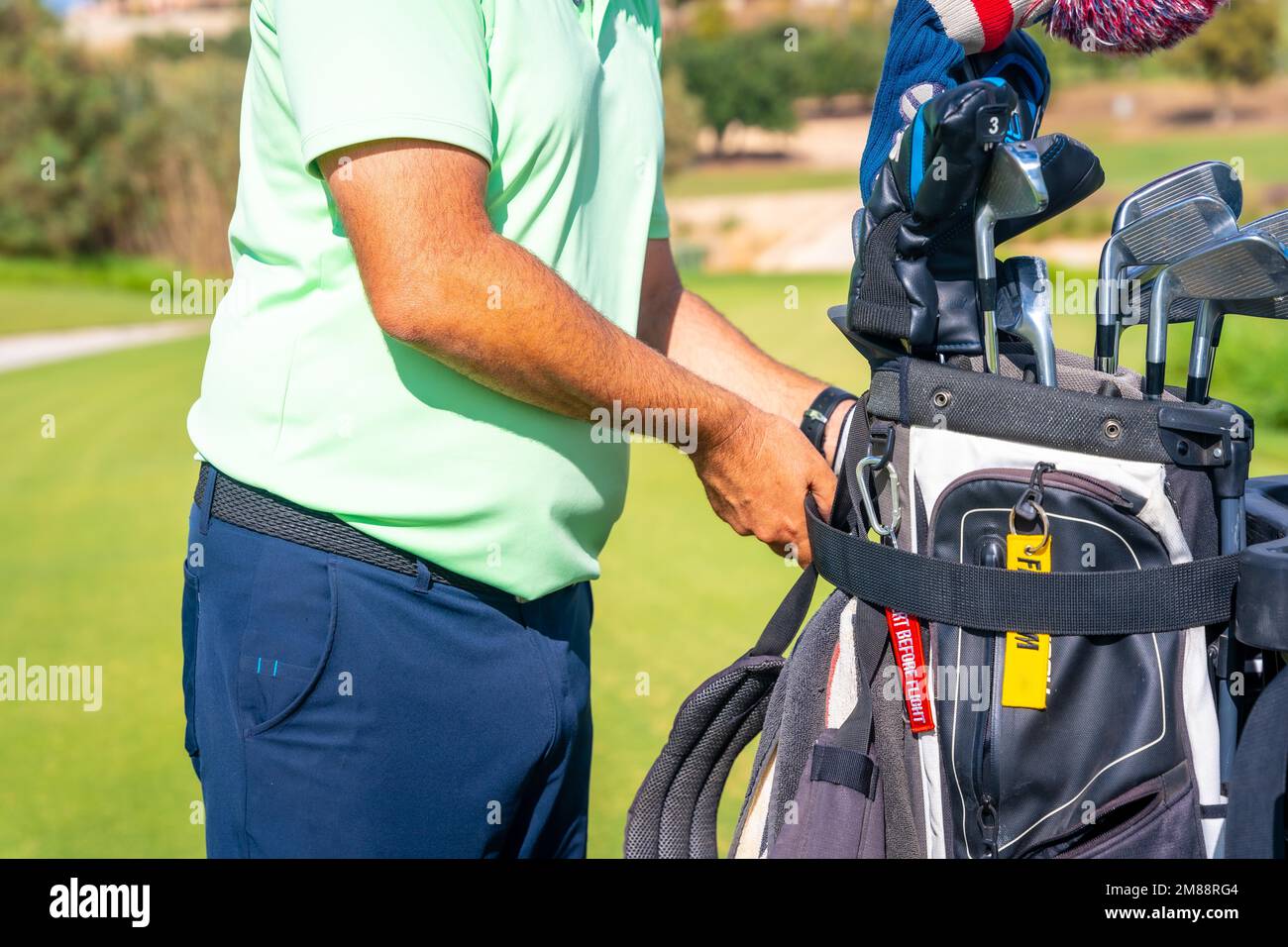 Man playing golf, picking up the bag of clubs and placing it in the