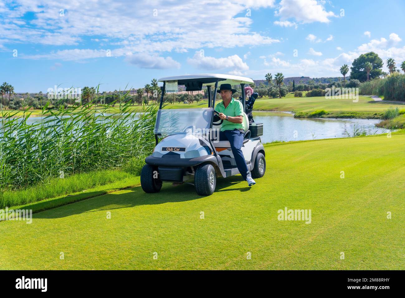 Man playing golf, in the buggy car moving around the golf course Stock Photo