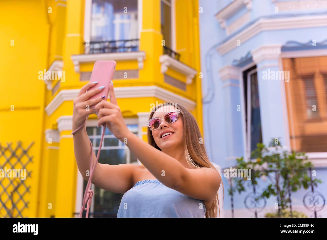 Portrait attractive young blonde woman taking a selfie, behind yellow ...