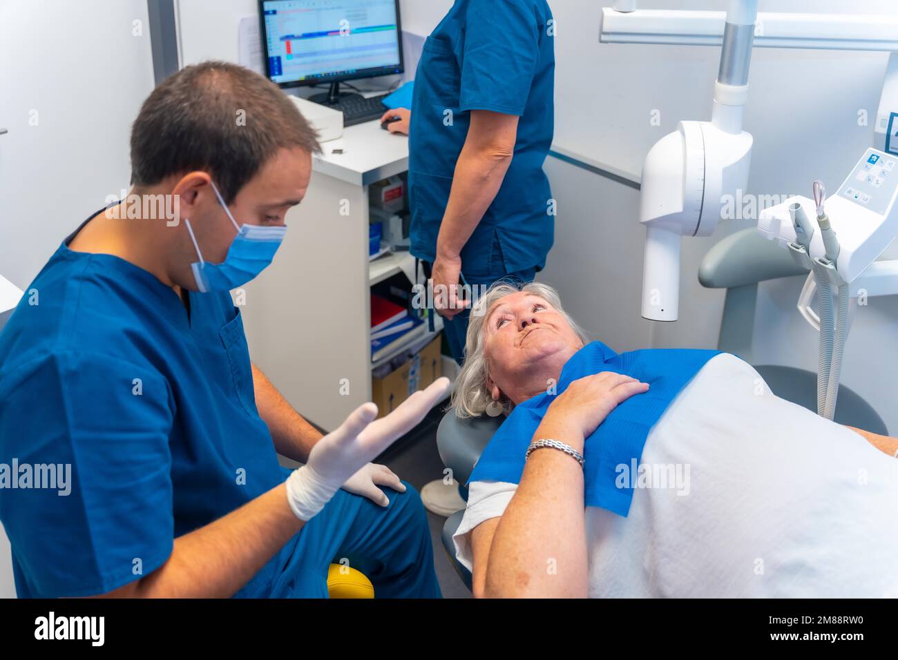 Dental clinic, dentist doctor and assistant explaining to an elderly woman the dental check-up Stock Photo