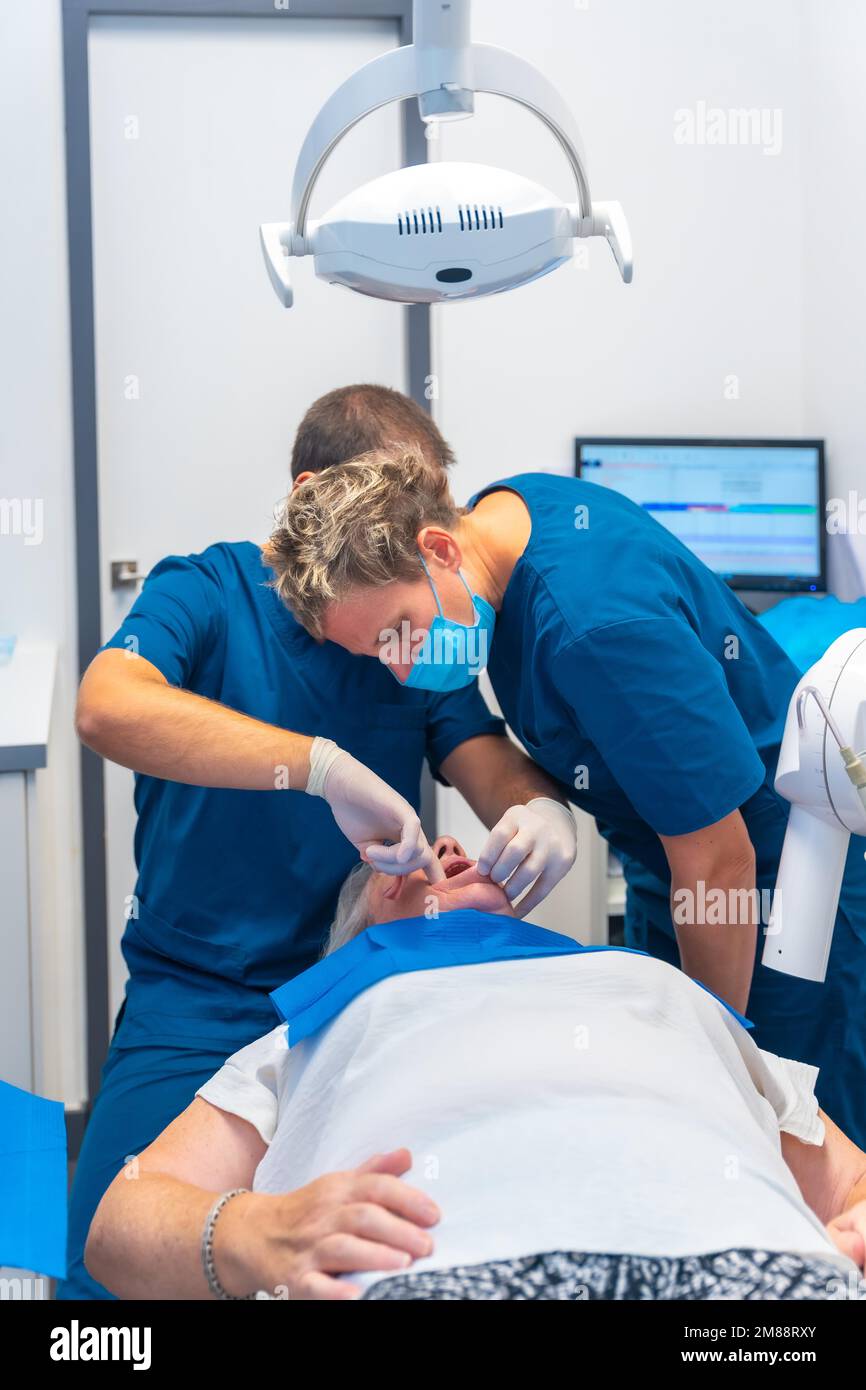 Dental clinic, dentist doctor and assistant examining the teeth of an elderly woman Stock Photo