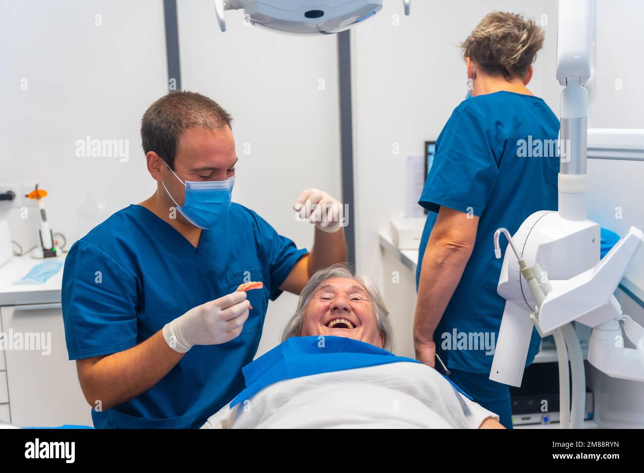 Dental clinic, dentist doctor having a good time with elderly woman lying on the table Stock Photo