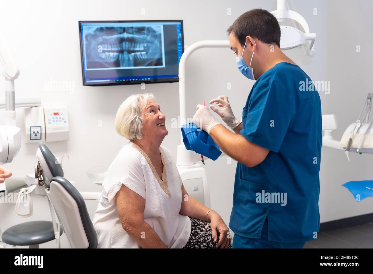 Dental clinic, dentist doctor having a good time with elderly woman lying on the table Stock Photo
