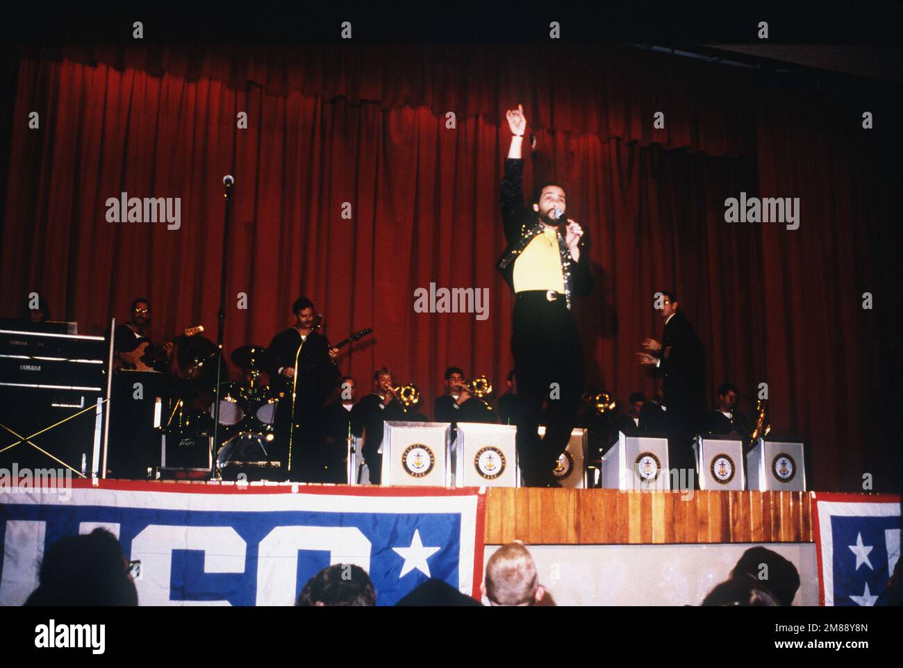 Entertainer Lee Greenwood, backed by the Pacific Fleet Band, sings at a United Service Organizations (USO) show in the base theater. Base: Naval Station, Rota Country: Spain (ESP) Stock Photo