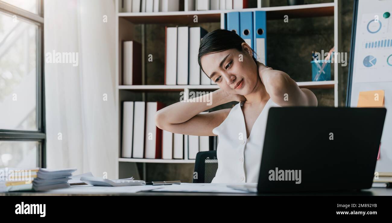 Business woman overwork on laptop computer and neck pain with at work in office, girl stress and illness chronic with office syndrome, health and Stock Photo