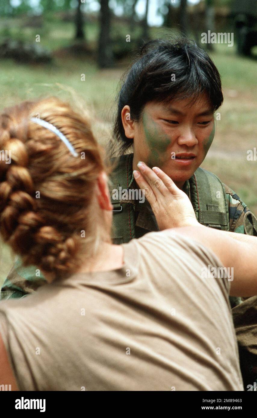 SPC Krissy M. Palacios, medic, assists PFC Kim S. young, company cook, with camouflage makeup as the two prepare for patrol during the joint Honduran/U.S. exercise Cabanas '88. Subject Operation/Series: CABANAS '88 Base: Palmerola Air Base Country: Honduras (HND) Stock Photo