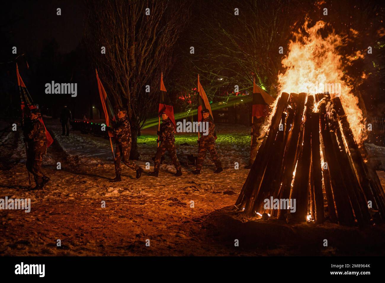 Vilnius, Lithuania. 12th Jan, 2023. Cadets carrying Lithuanian flags pass by a bonfire near the Vilnius TV tower on the eve of the 32nd anniversary of the Day of the Defenders of Freedom 'Battle for the Freedom of Nations' in Vilnius The ceremonial lighting of bonfires took place near the Vilnius TV tower and on the Independence Square on the eve of the day of remembrance for the victims of the January 1991 events, when 14 people died and many were injured during the assault by Soviet troops on the television center in Vilnius. Credit: SOPA Images Limited/Alamy Live News Stock Photo