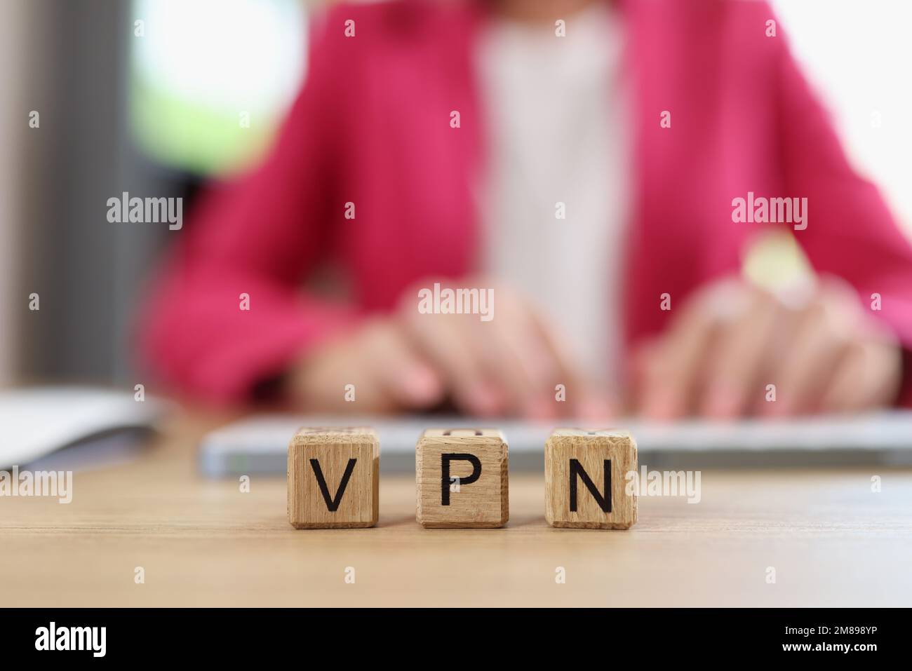 Letters VPN on wooden cubes - Virtual Private Network and Internet user works on computer in background. Stock Photo