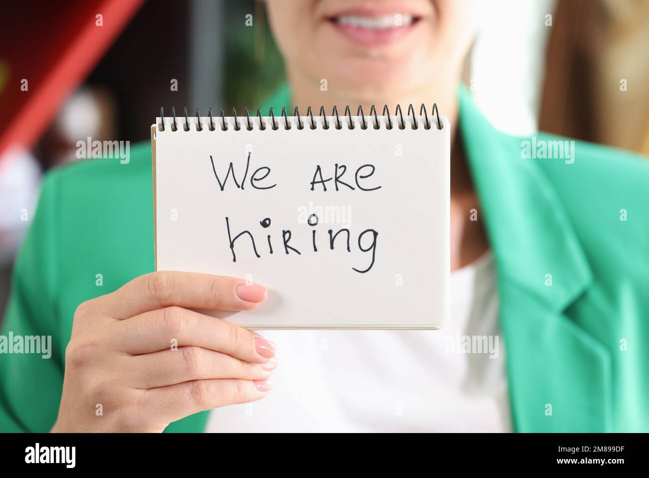 Female HR manager showing paper with message we are hiring. Stock Photo