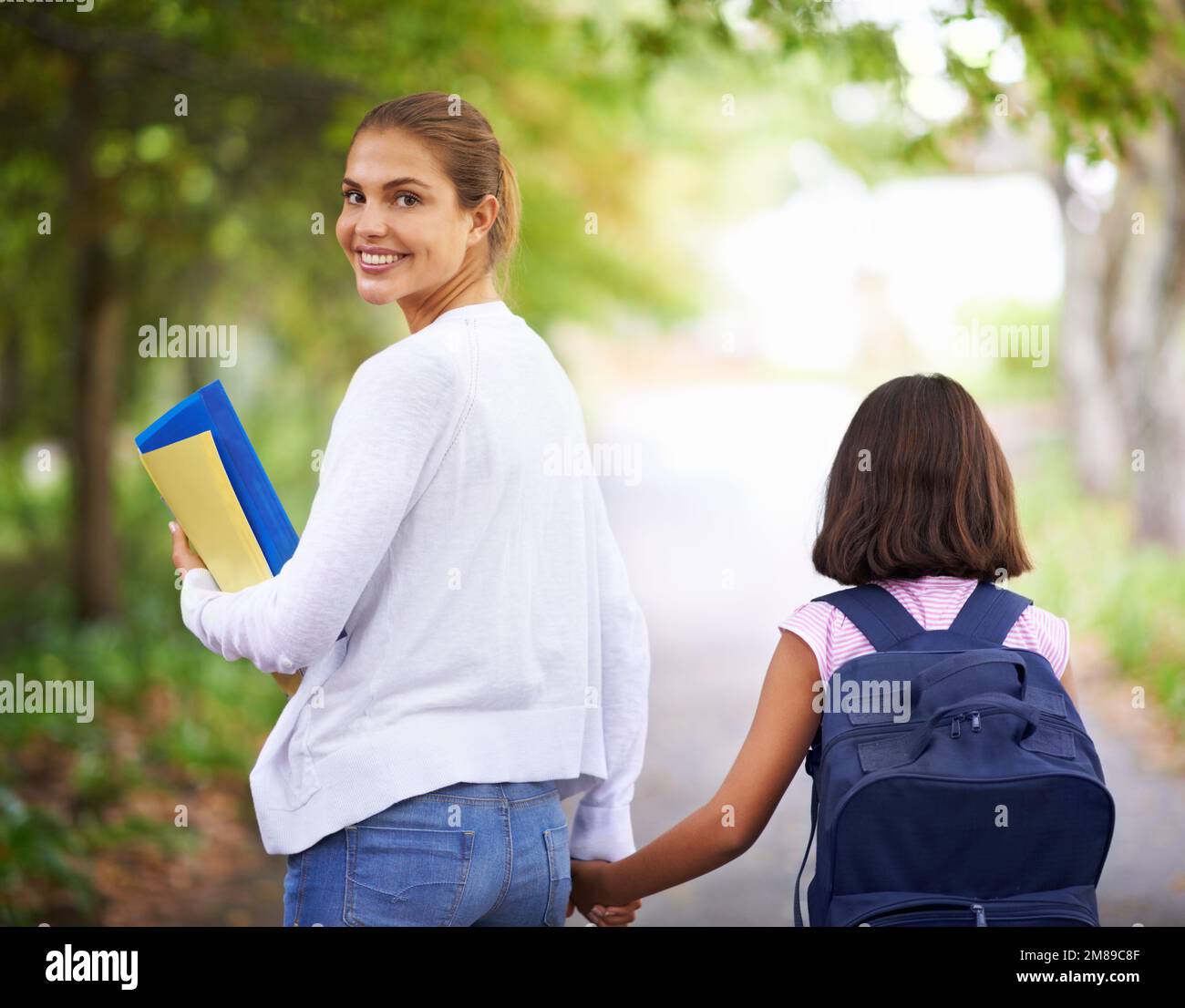 Walking to school. Rear view of a teacher walking her student to school