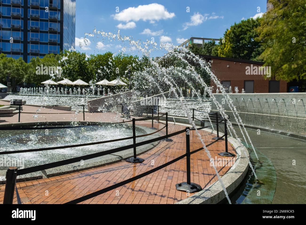 Fountain in downtown city. Pathway under the water. Buildings in the