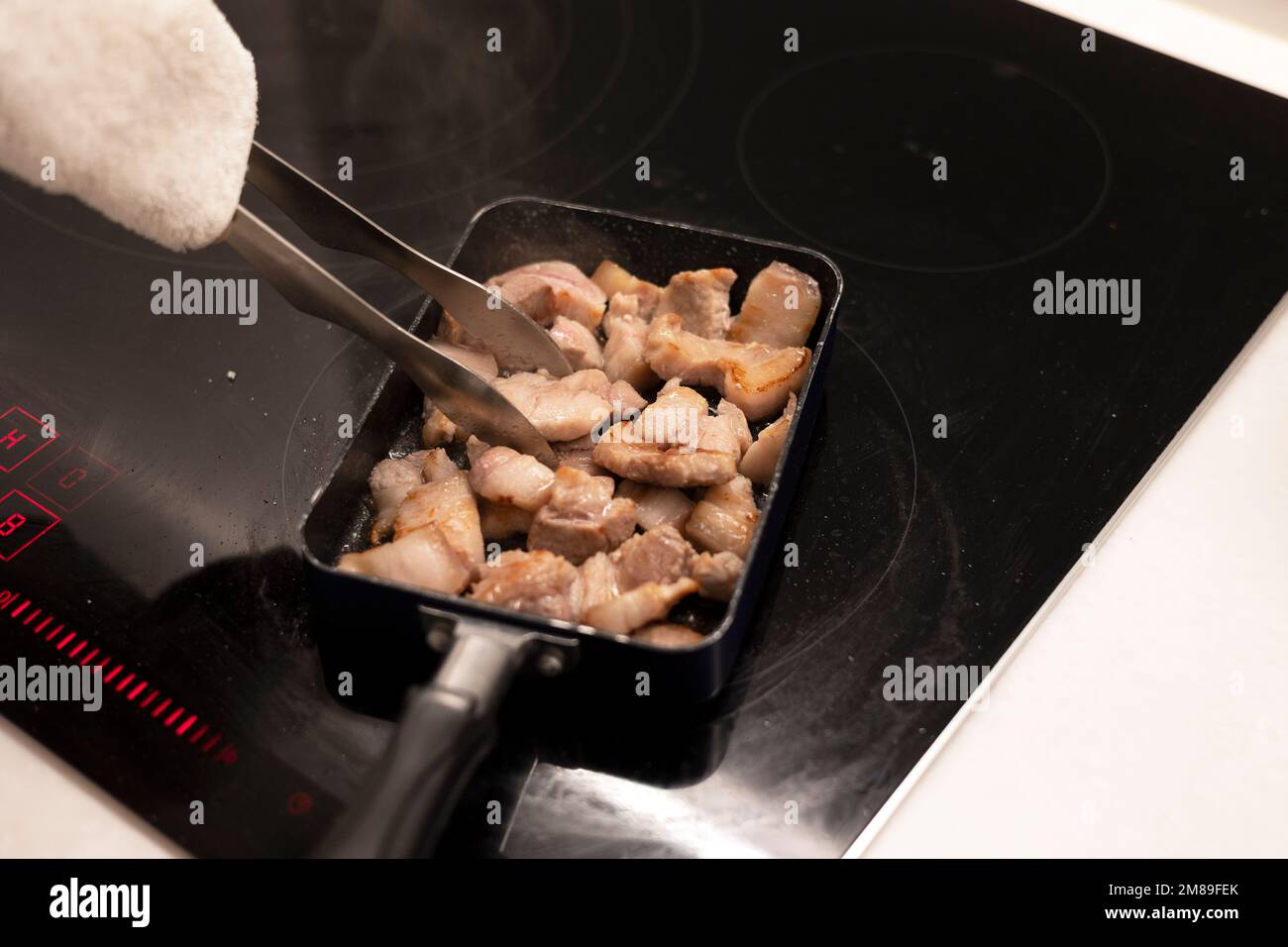 Cooking pork belly meat with frying pan and tongs Stock Photo Alamy