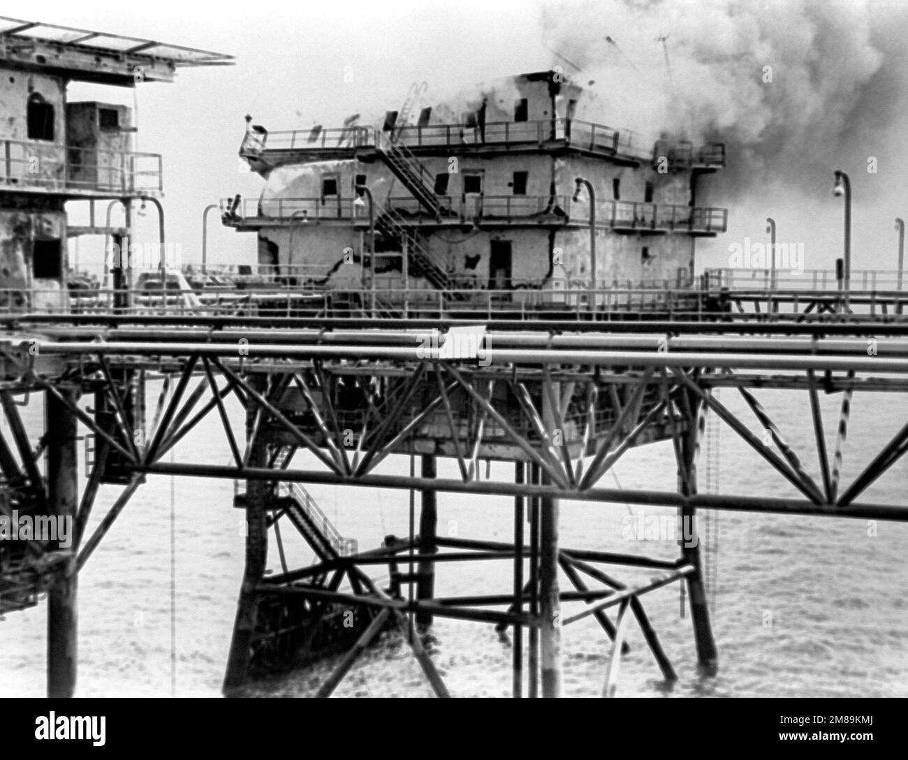 The main building of the Iranian Sassan oil platform burns after being hit by a BGM-71 Tube-launched, Optically-tracked, Wire-guided (TOW) missile fired from a Marine AH-1 Cobra helicopter. The attack was part of Operation Praying Mantis which was launched after the guided missile frigate USS SAMUEL B. ROBERTS (FFG-58) struck an Iranian mine on April 14, 1988. Subject Operation/Series: PRAYING MANTIS Country: Unknown Stock Photo