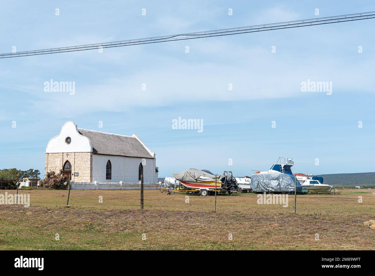 Witsand, South Africa - Sep 24, 2022: The historic Barry Memorial Church, in Port Beaufort at Witsand in the Western Cape Province. Fishing boats are Stock Photo