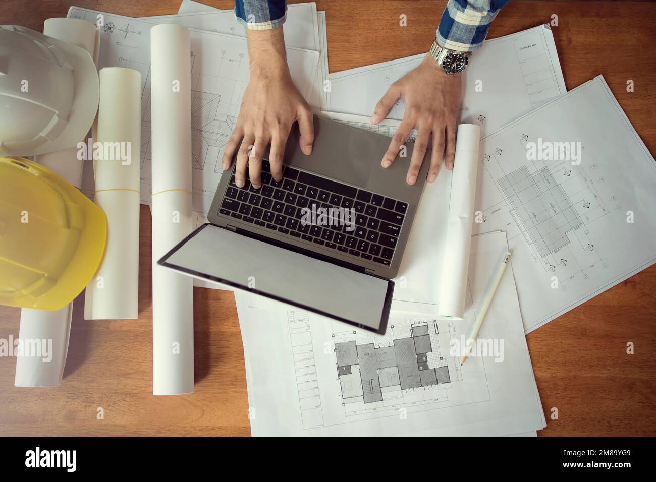 Architect working with laptop and blueprints, checking engineer in workplace for architecture plan, construction project sketch. Stock Photo