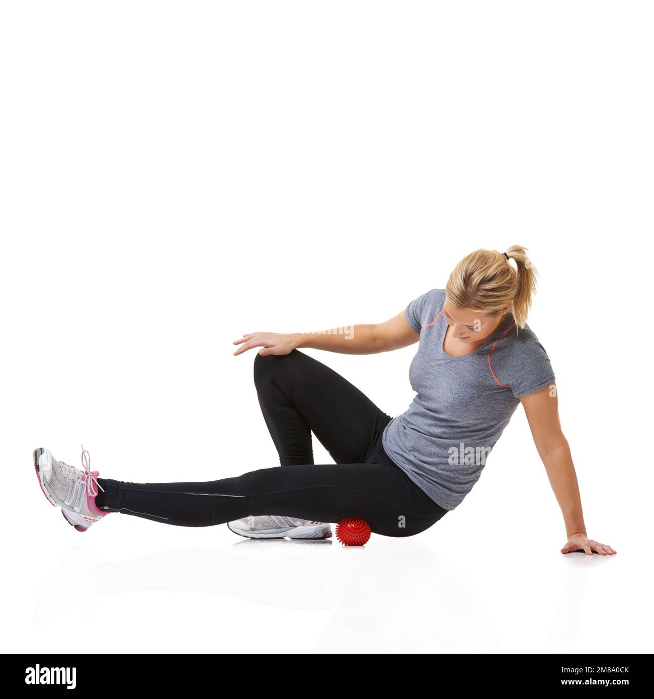 Rolling out her thigh muscles. A young woman working out using an