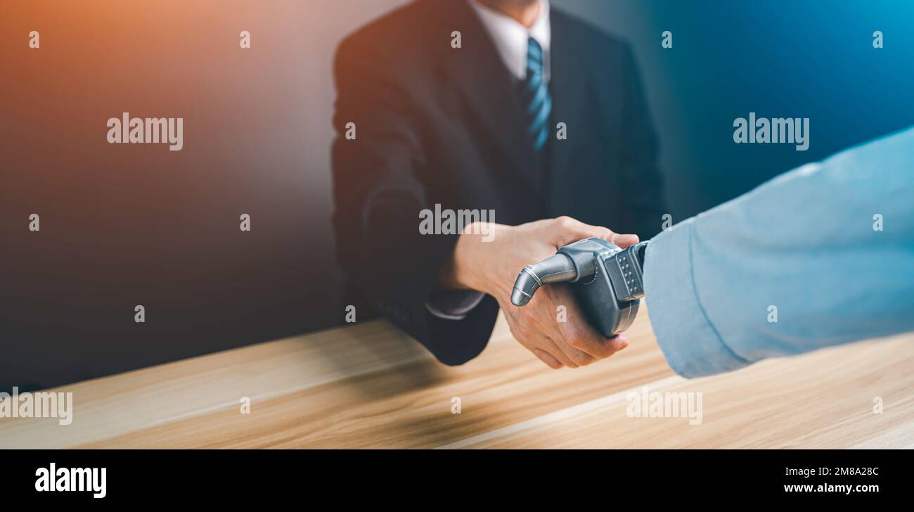 Hand of a businessman in a suit shaking hands and make deal with a droid robot. Concept of innovation in business with artificial intelligence. Stock Photo