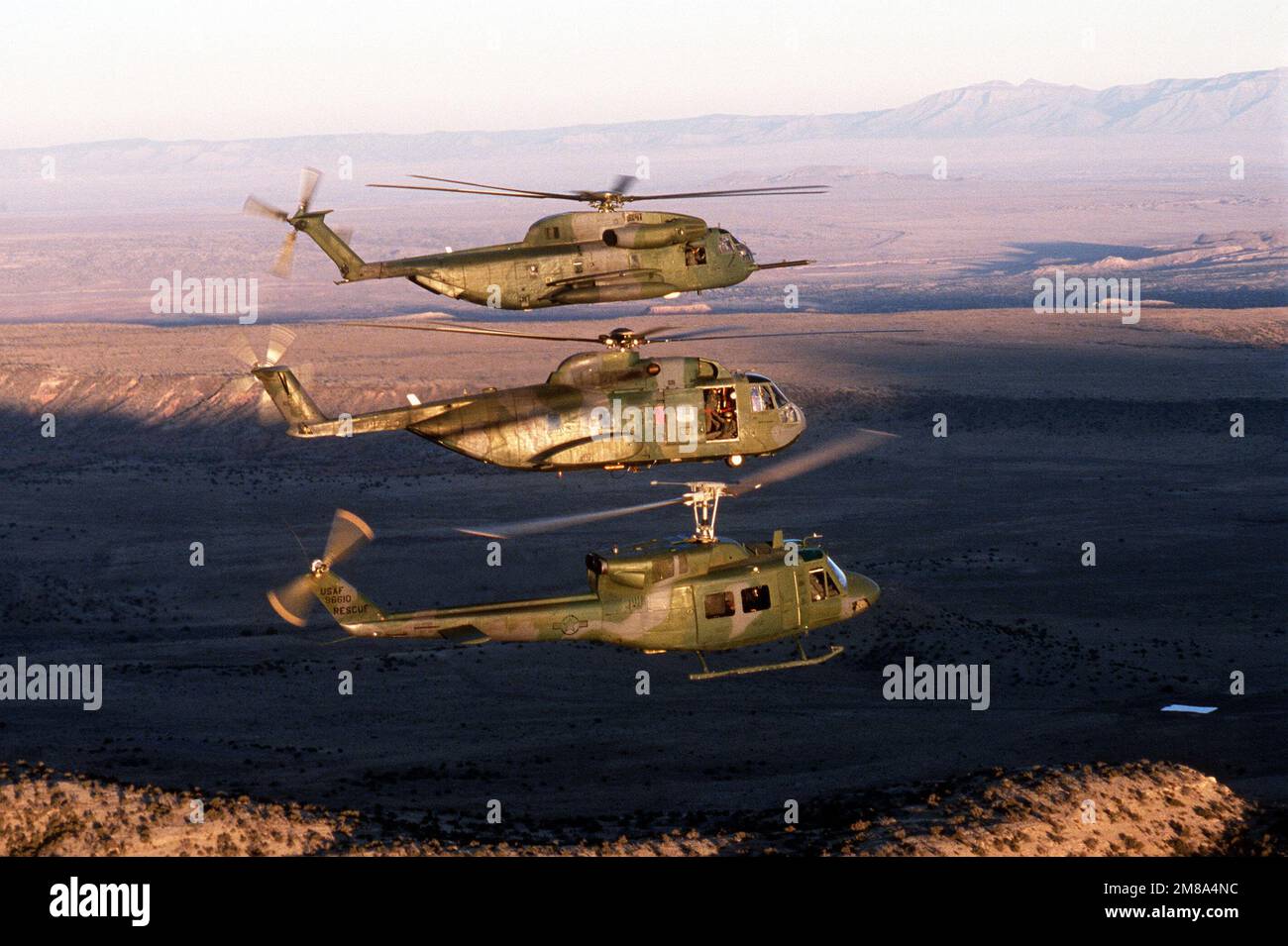 An HH-53 Super Jolly, an H-3 Jolly Green Giant and a UH-1 Iroquois helicopter fly in formation near the 531st Field Training Detachment's helicopter maintenance school at Kirtland Air Force Base. State: New Mexico (NM) Country: United States Of America (USA) Stock Photo