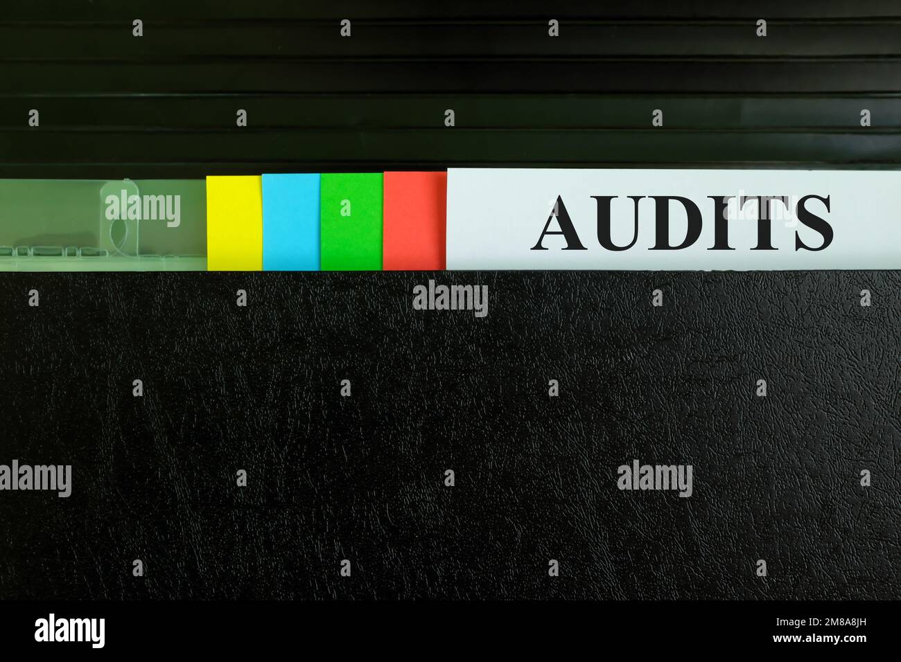 Hand picking audit report file record in black binder folder. Auditing