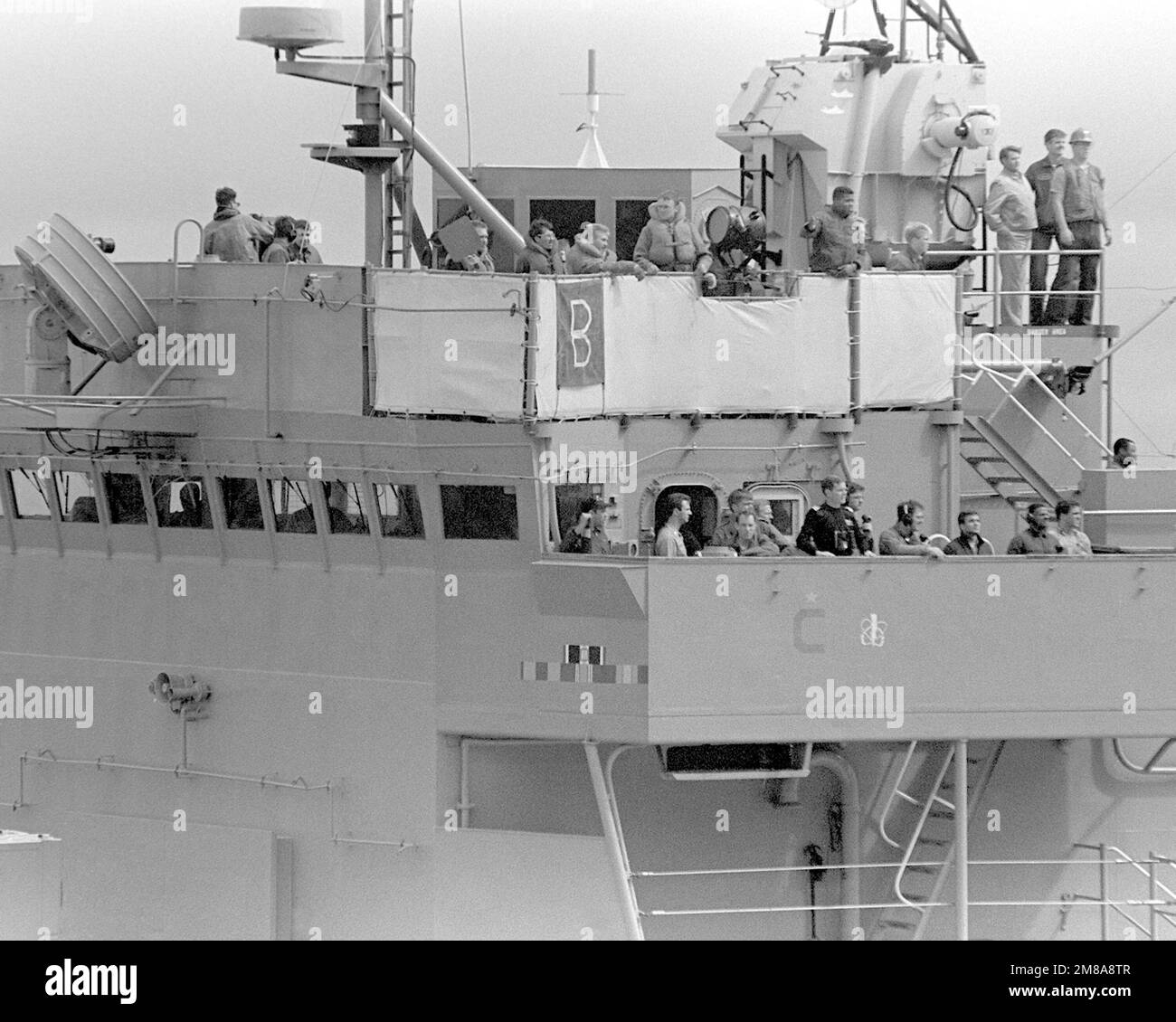 Officers and crew watch from the superstructure of the frigate USS