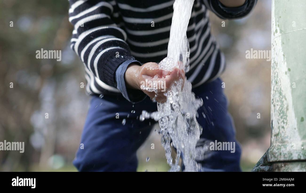 Closeup of flowing water faucet child hand and mouth drinking outdoors