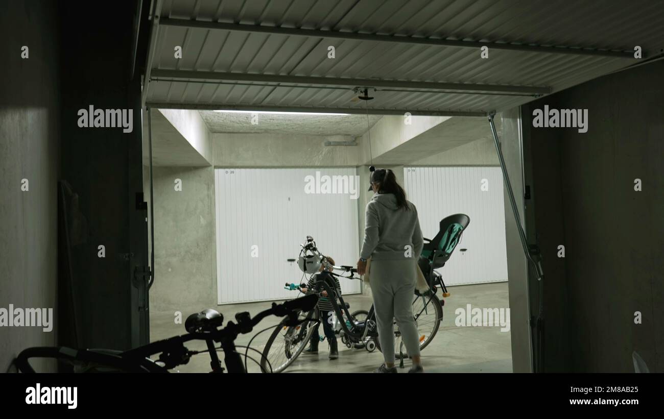 Mother opening storage room in underground parking space. Person opens metal gate interior Stock