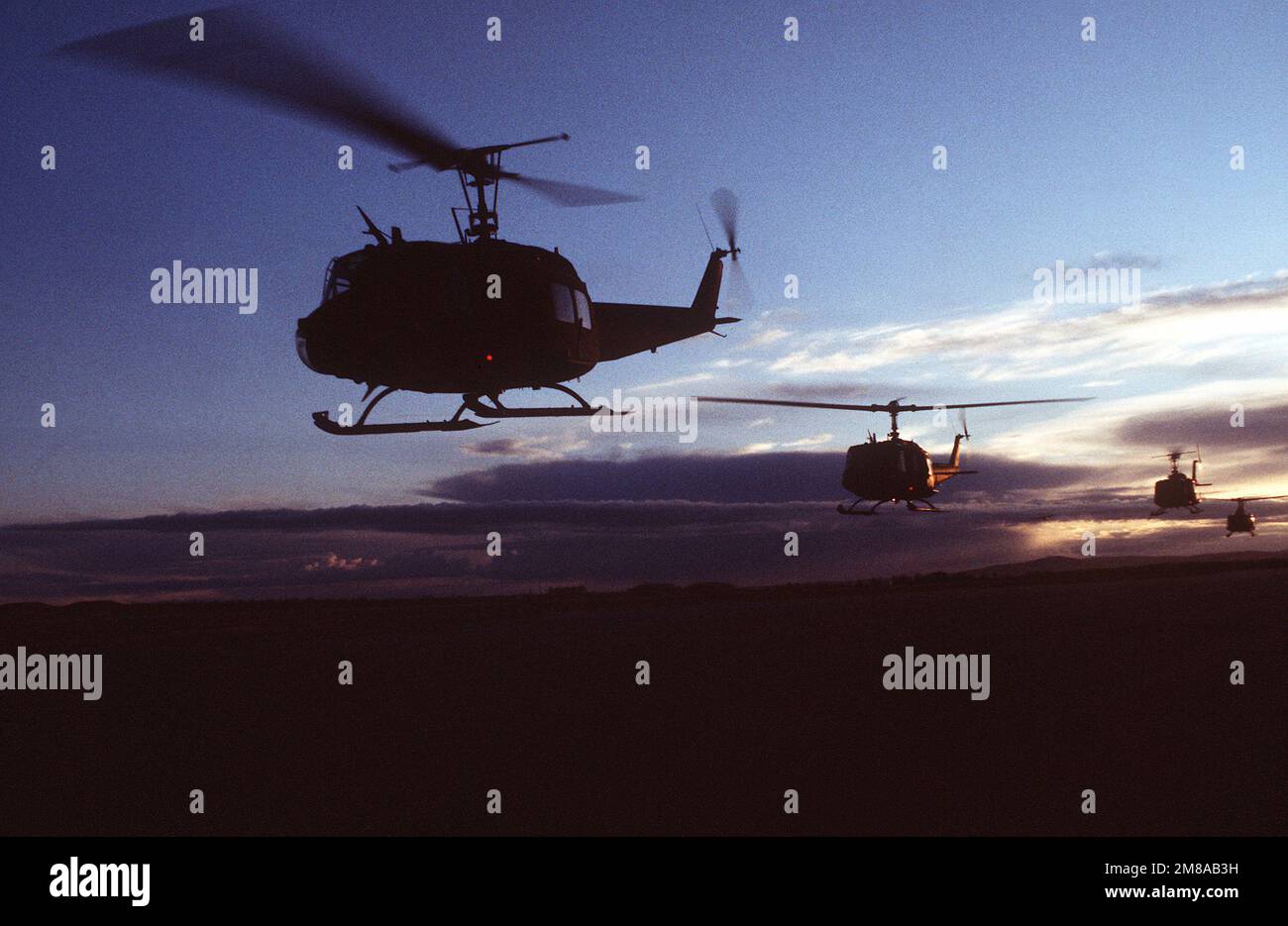 A line of UH1H Iroquois helicopters carry personnel into the field for