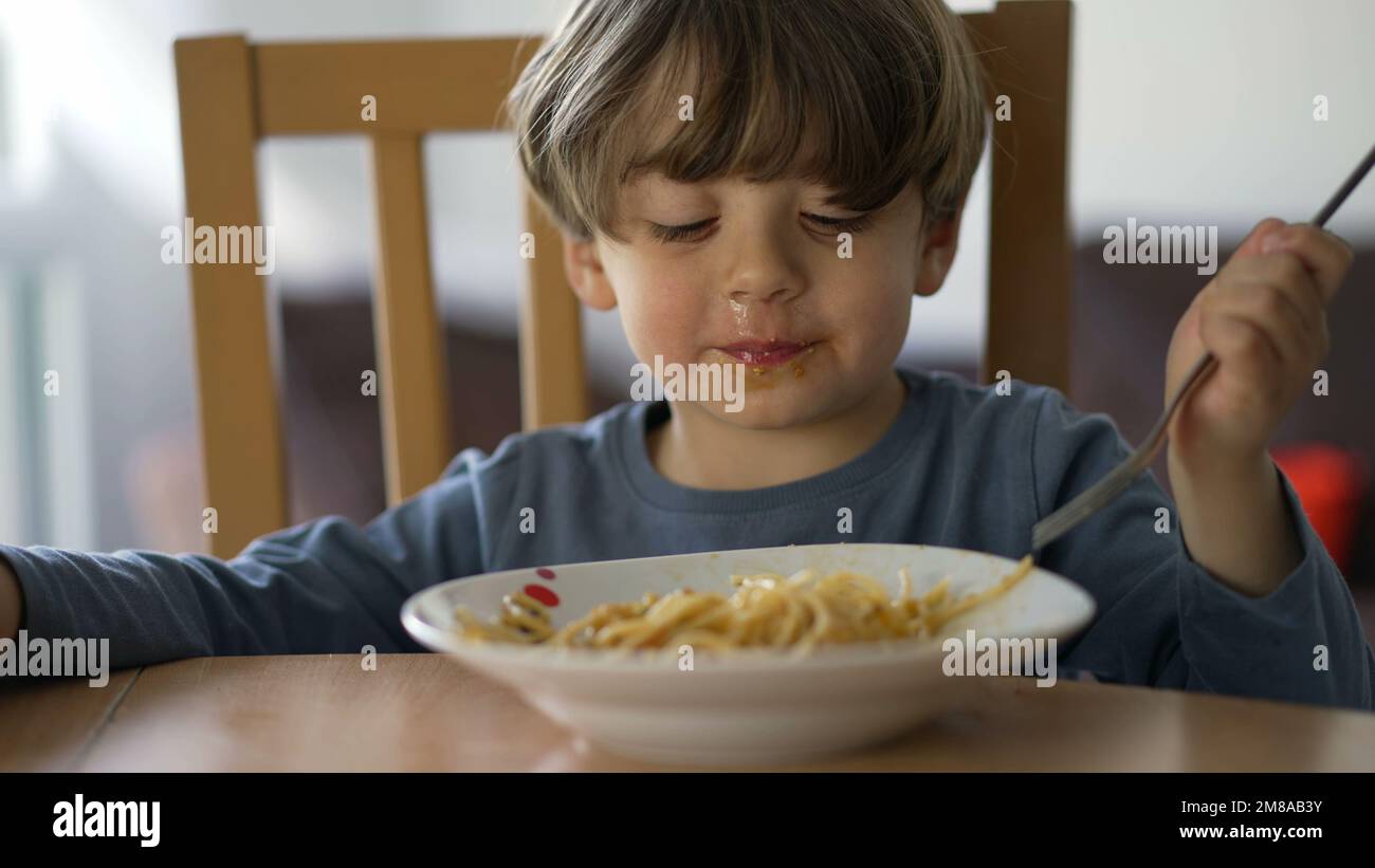 One little boy eating pasta with fork. Child eats lunch meal carb food ...