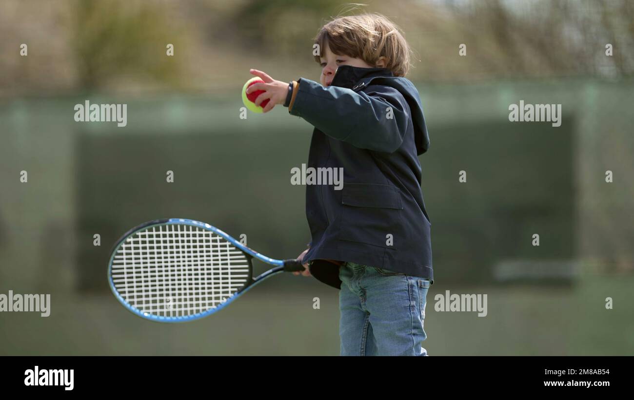 One little boy holding tennis racket playing outside Stock Photo - Alamy