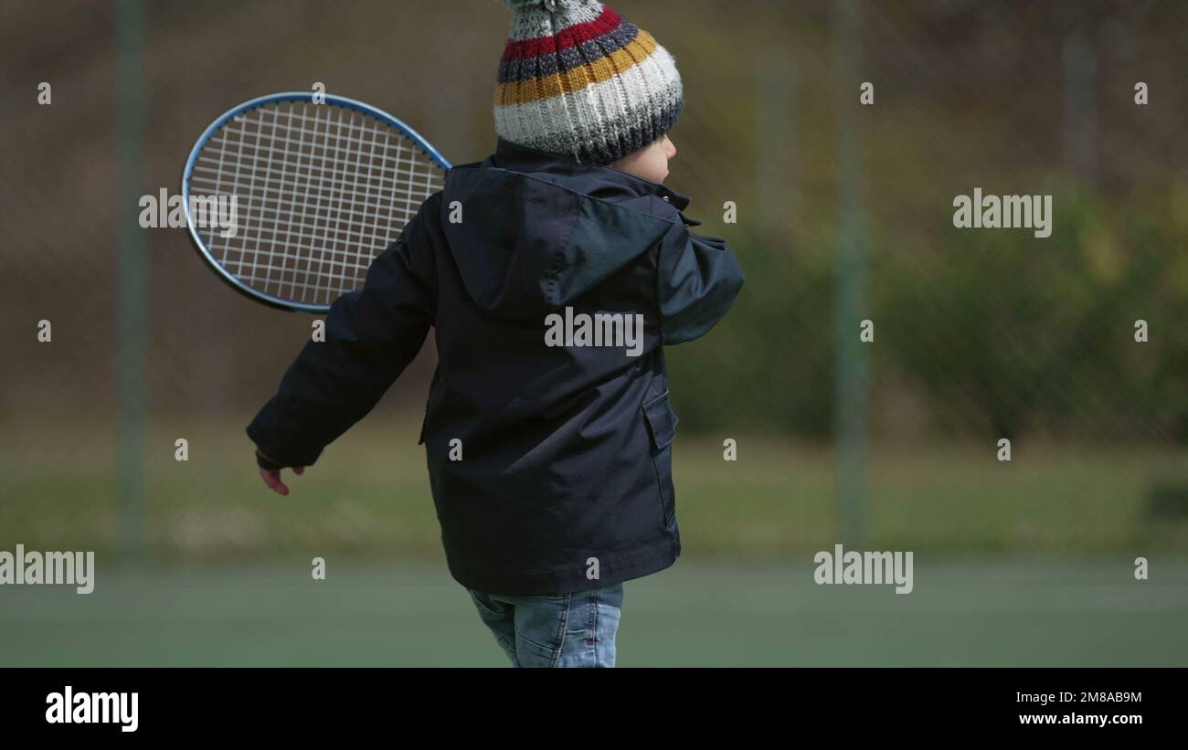 One little boy holding tennis racket playing outside Stock Photo - Alamy
