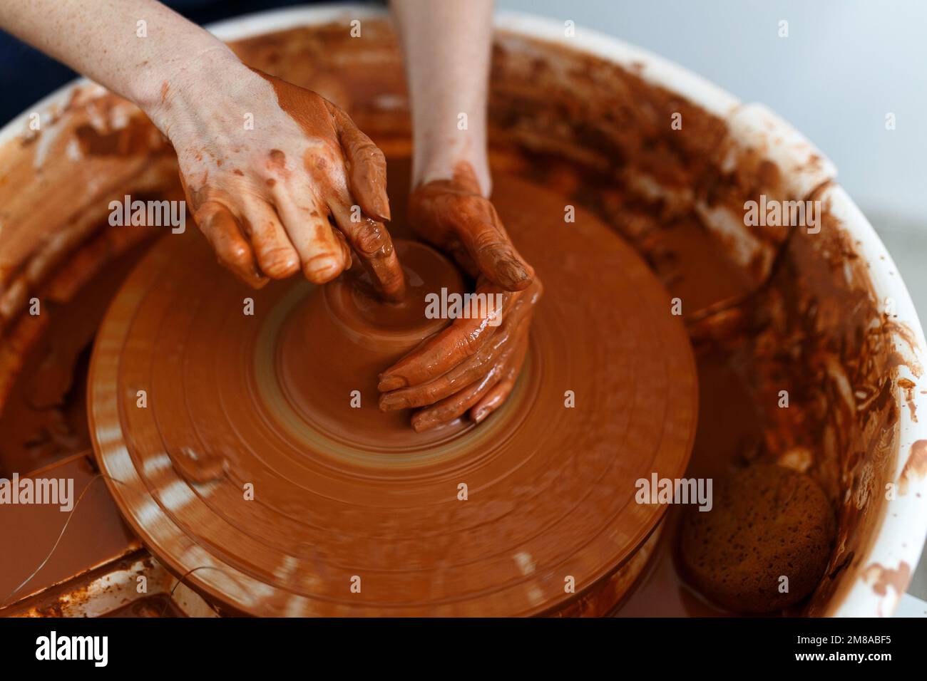 Cropped Image of Unrecognizable Female Ceramics Maker working with Pottery Wheel in Cozy Workshop Makes a Future Vase or Mug,Creative People Handcraft Stock Photo