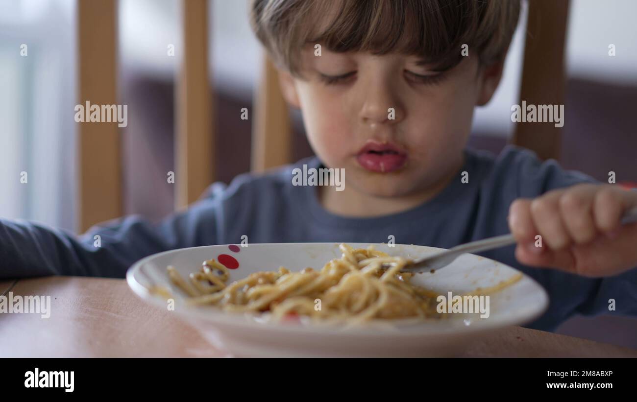 One little boy eating pasta with fork. Child eats lunch meal carb food