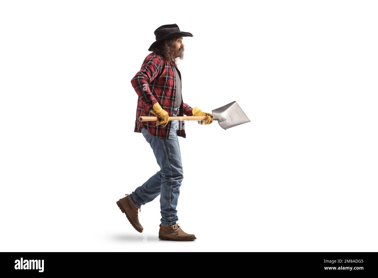 Full length profile shot of a farmer walking and holding a shovel ...