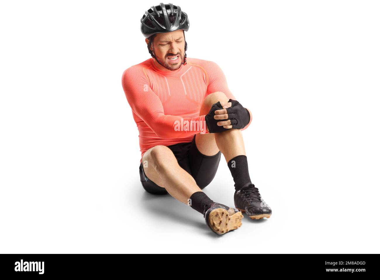 Injured bicycle rider sitting on the ground and holding his painful