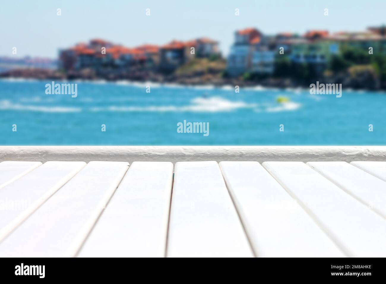 Plank wooden surface against defocused blue sea background with seaside resort Stock Photo