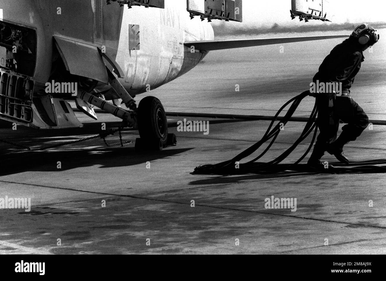 AIRMAN Grisselle Martinez drags power cables away from an A-7 Corsair